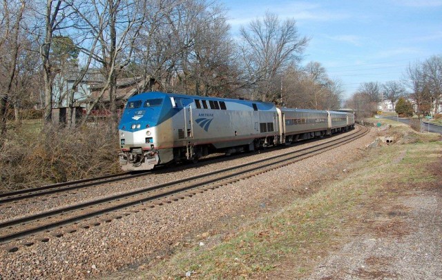 Amtrak's afternoon train to Kansas City has just departed Kirkwood Station, which is just behind the overhead bridge to the rear of the train.