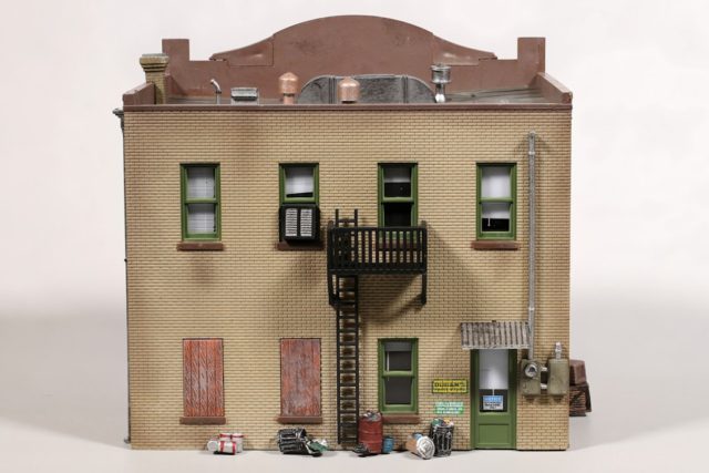 The rear wall features a fire escape, electric meter, and trash and paint cans.