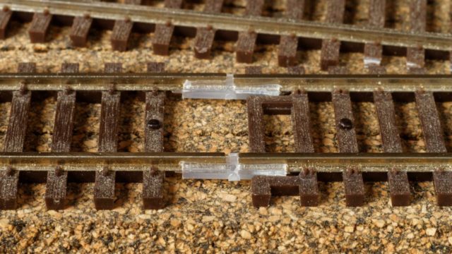 Here's a typical joint between flex-track (on the left) and sectional track (on right). A tie has been removed from the flex-track to allow room for the insulated rail joiners. Note that a hole was drilled in the flex-track last tie and a track nail added to ensure alignment. The missing tie will need to be added back before ballasting.