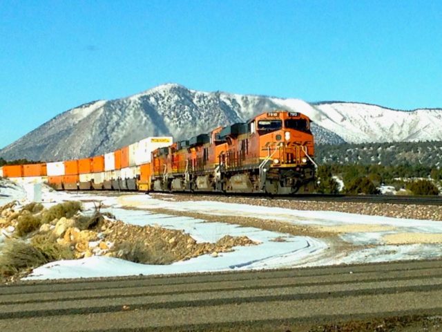 The ultimate of “grab” shots, taken with my cell phone through the windshield when this BNSF stack train appeared just east of Flagstaff, AZ. Those are the Eisenhower peaks (12,000+ feet) in the background.