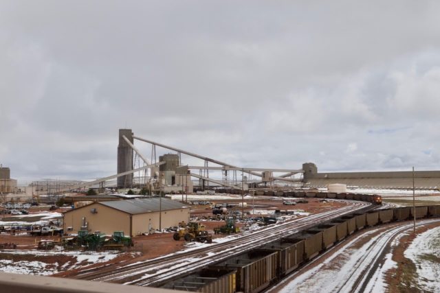 This is the Powder River coal basin. Empty hoppers in the foreground are already in the queue on a balloon track on a never stopping route through the loaders and out again. The approaching train (headlight) is exiting the loader and starting its eastern run that may not end until it reaches the Tidewater in Virginia.